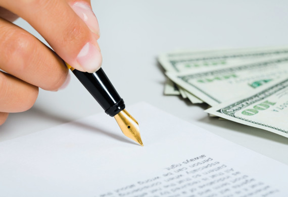 Female hand is signing the business document near money